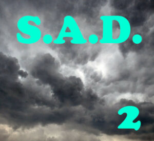 S.A.D. 2 est écrit en tuquoise, sur un ciel de gros nuages sombres