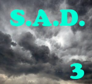 S.A.D. 3 est écrit en tuquoise, sur un ciel de gros nuages sombres